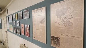 Die Südseite des Themenraums mit Ausstellungstafeln zum Kalten Krieg und zum Wettrüsten. Im Vordergrund ist ein Faksimile der Berichterstattung der Augsburger Allgemeinen Zeitung zur Kubakrise im Oktober 1962 zu sehen.