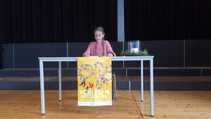 Laura Krebs (6a) artikuliert sehr klar, setzt gekonnt Kunstpausen und nimmt die Zuhörer durch ihren ruhigen, souveränen Vortrag mit in die geheimnisvoll-spannende Welt der „Duftapotheke – Ein Geheimnis liegt in der Luft“ von Anna Ruhe.